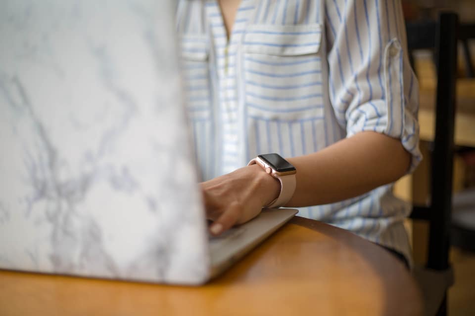 Person registering a domain name on a laptop in a cafe