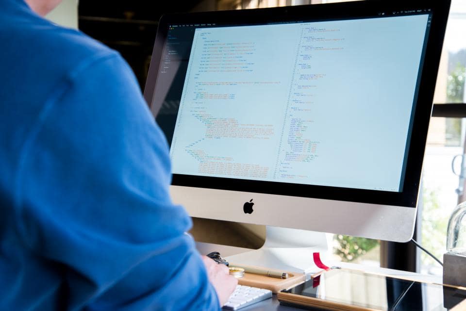 Developer comparing a visual page builder with a code editor on two screens