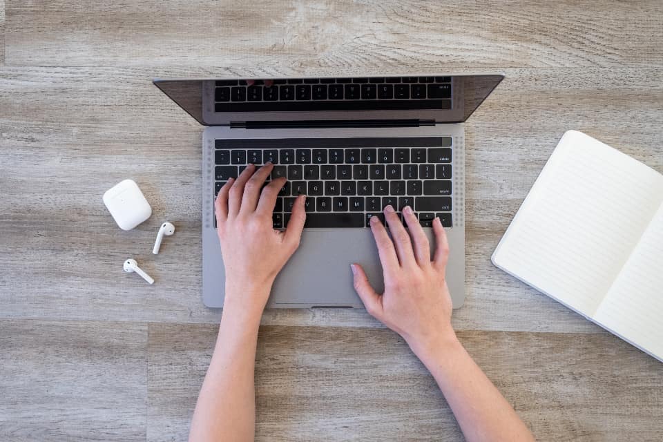 Copywriter planning website page content on a notepad beside a laptop